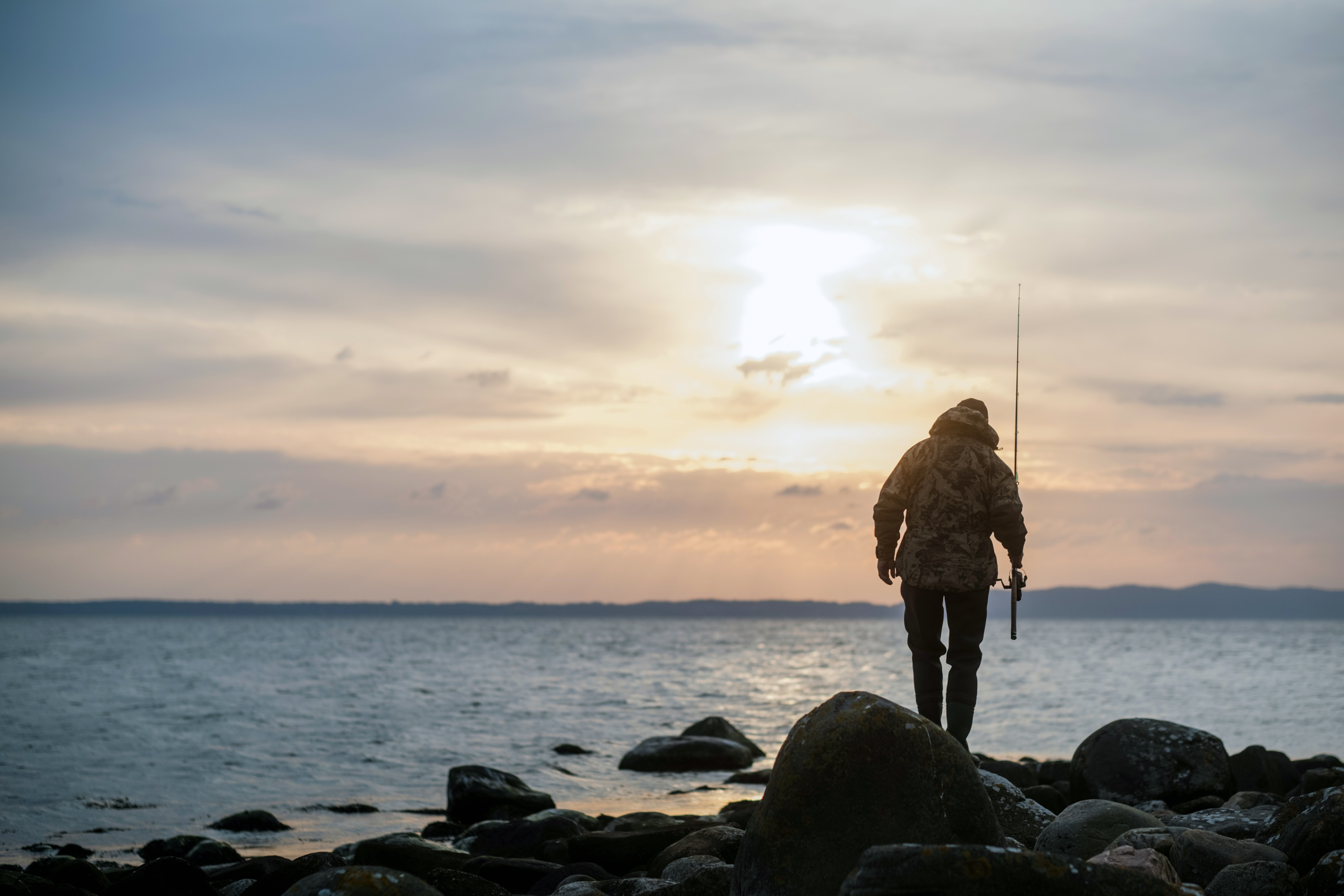 A man is going fishing among the rocks at sunrise