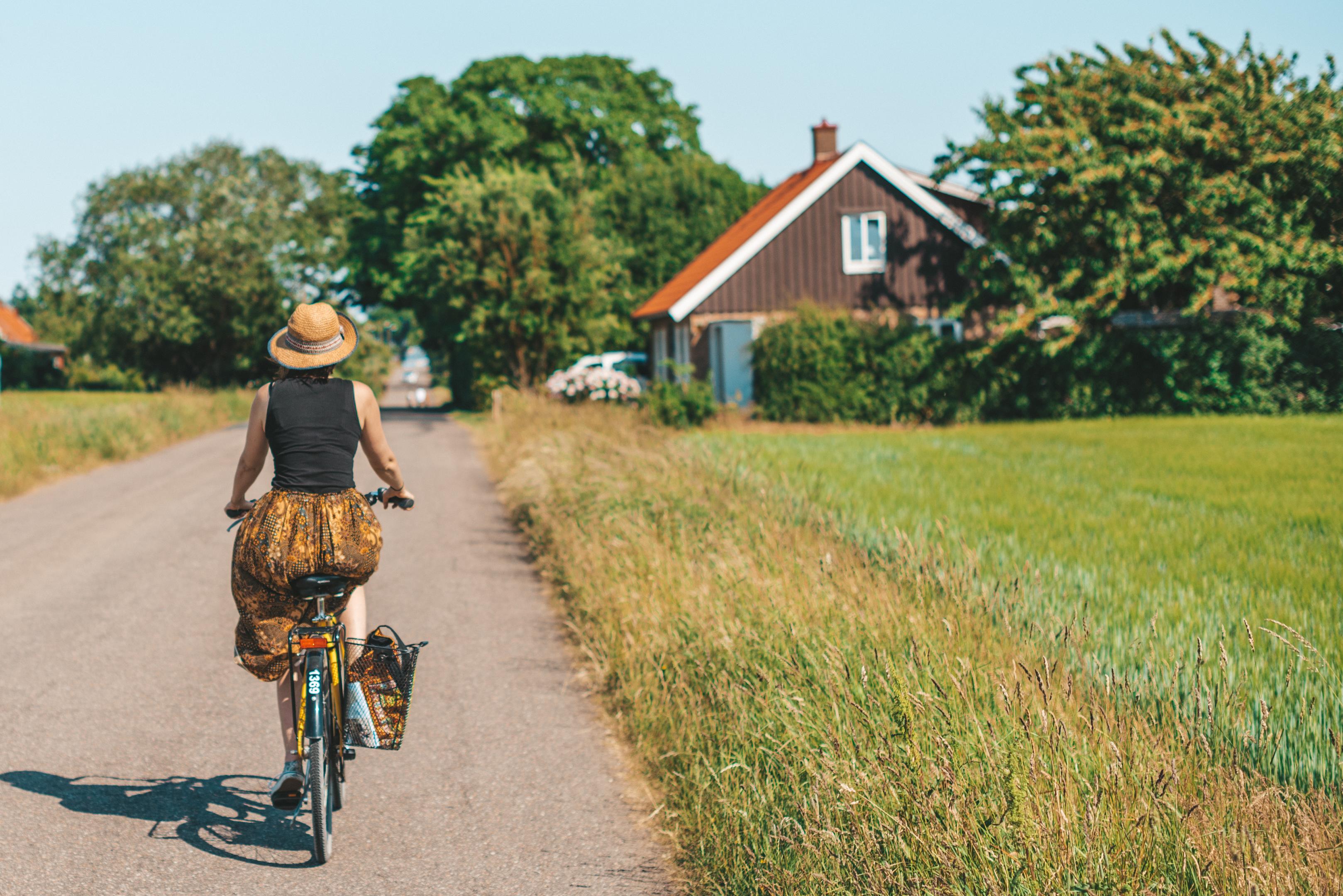 Eine Frau beim Radfahren auf einer Landstraße an einem Sommertag