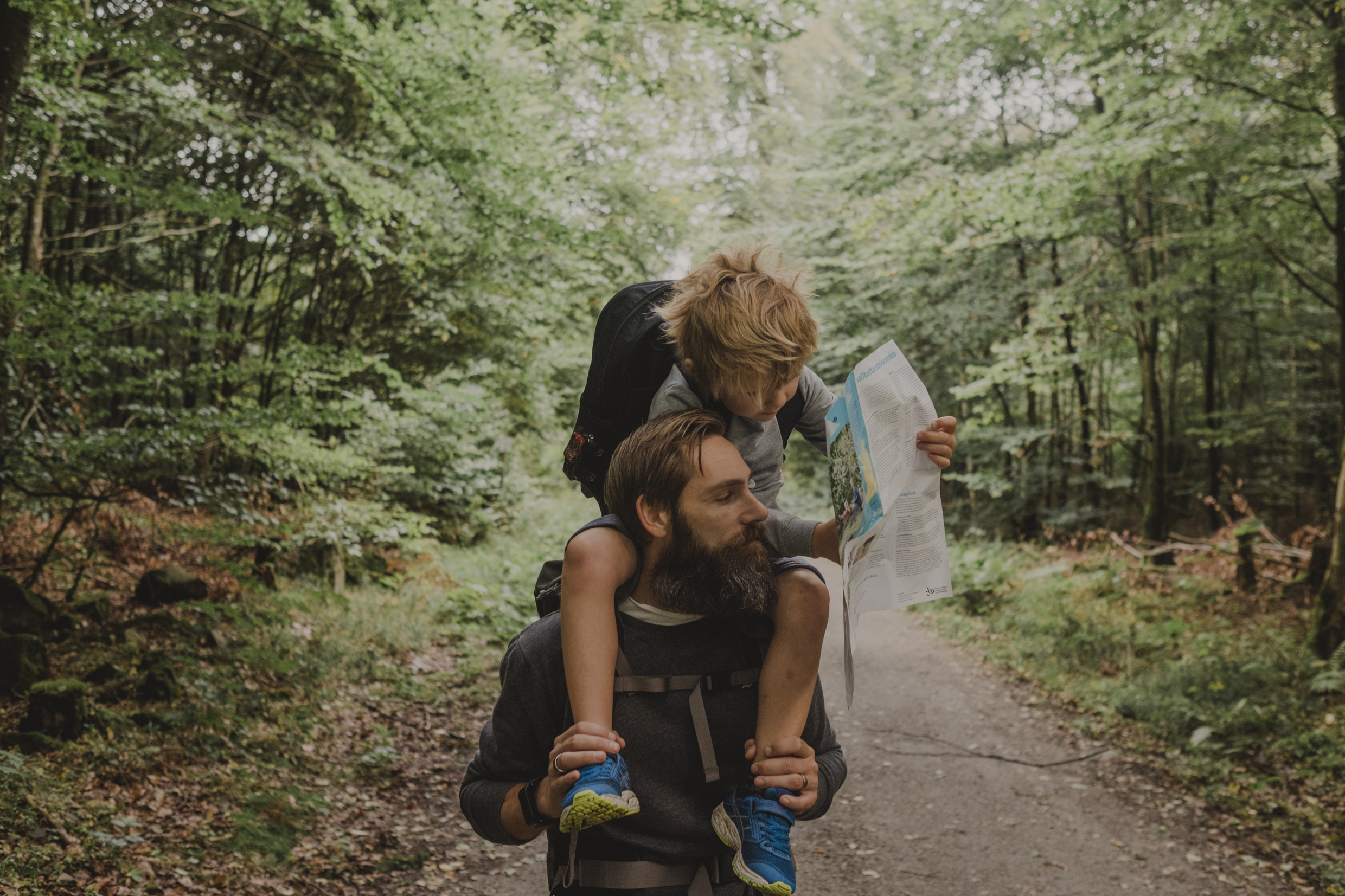 Pojke sitter på sin pappas axlar och tittar på en karta