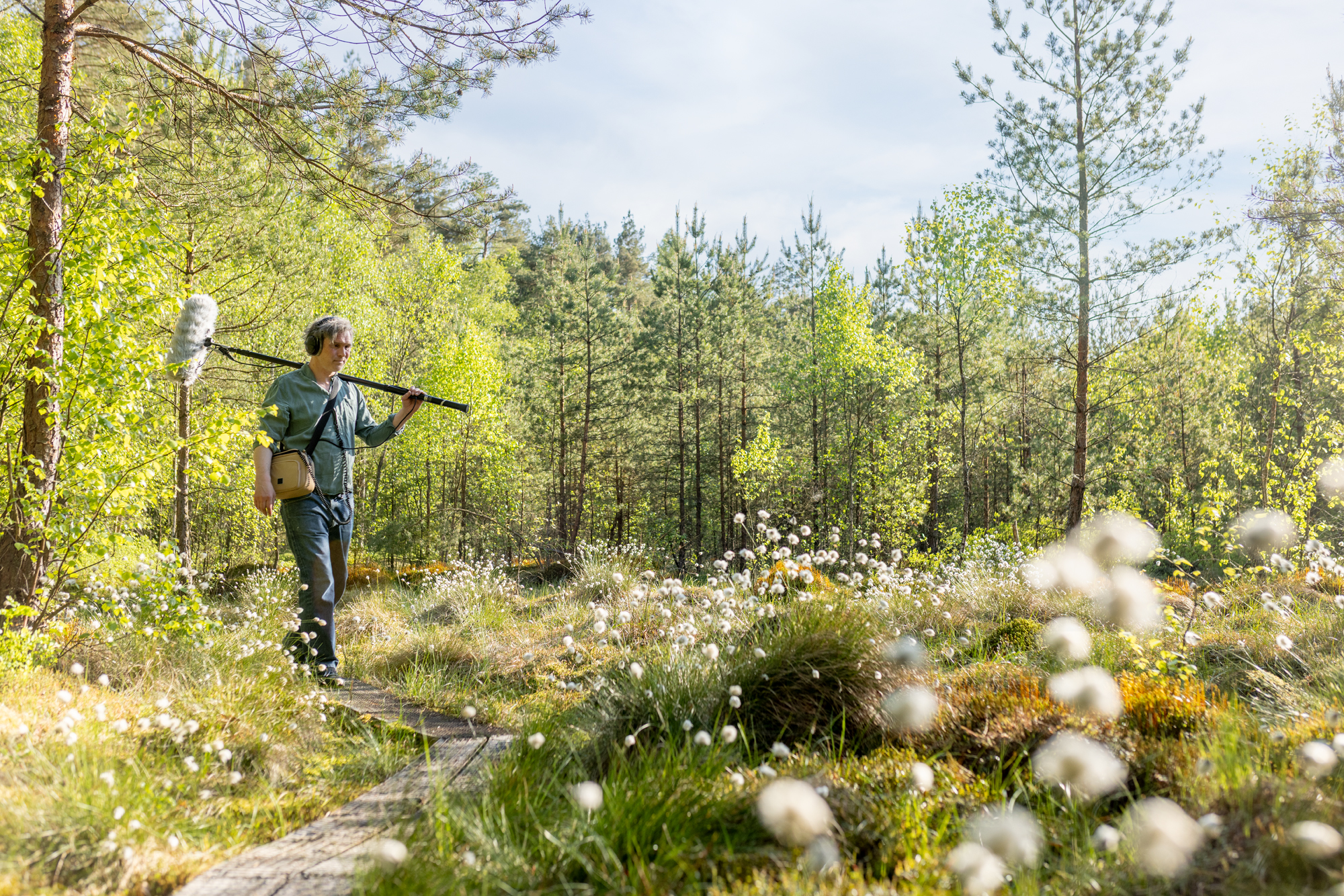 A man with a microphone walking through a forest.