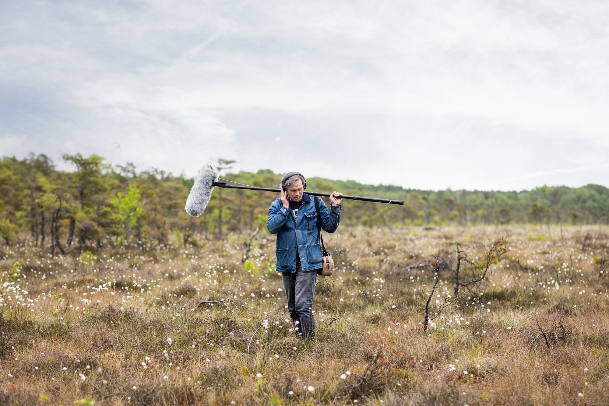 A man in a field holding a microphone.