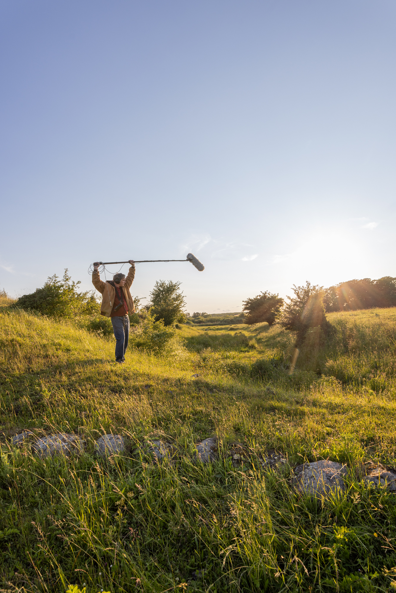 A man holding a microphone on top of a lush green field.