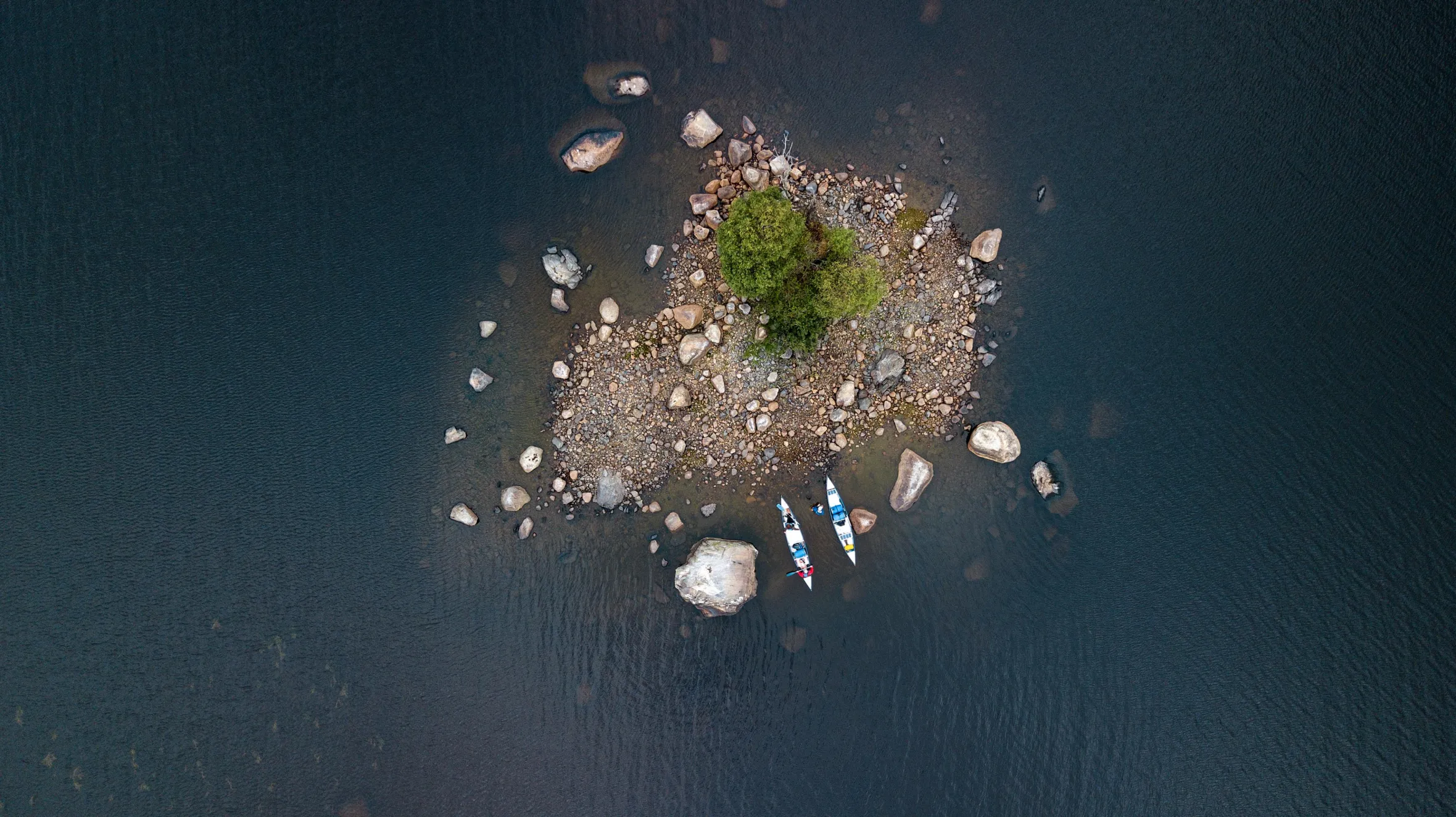 Blick von oben auf Kanus, die an einer kleinen Insel angedockt sind.