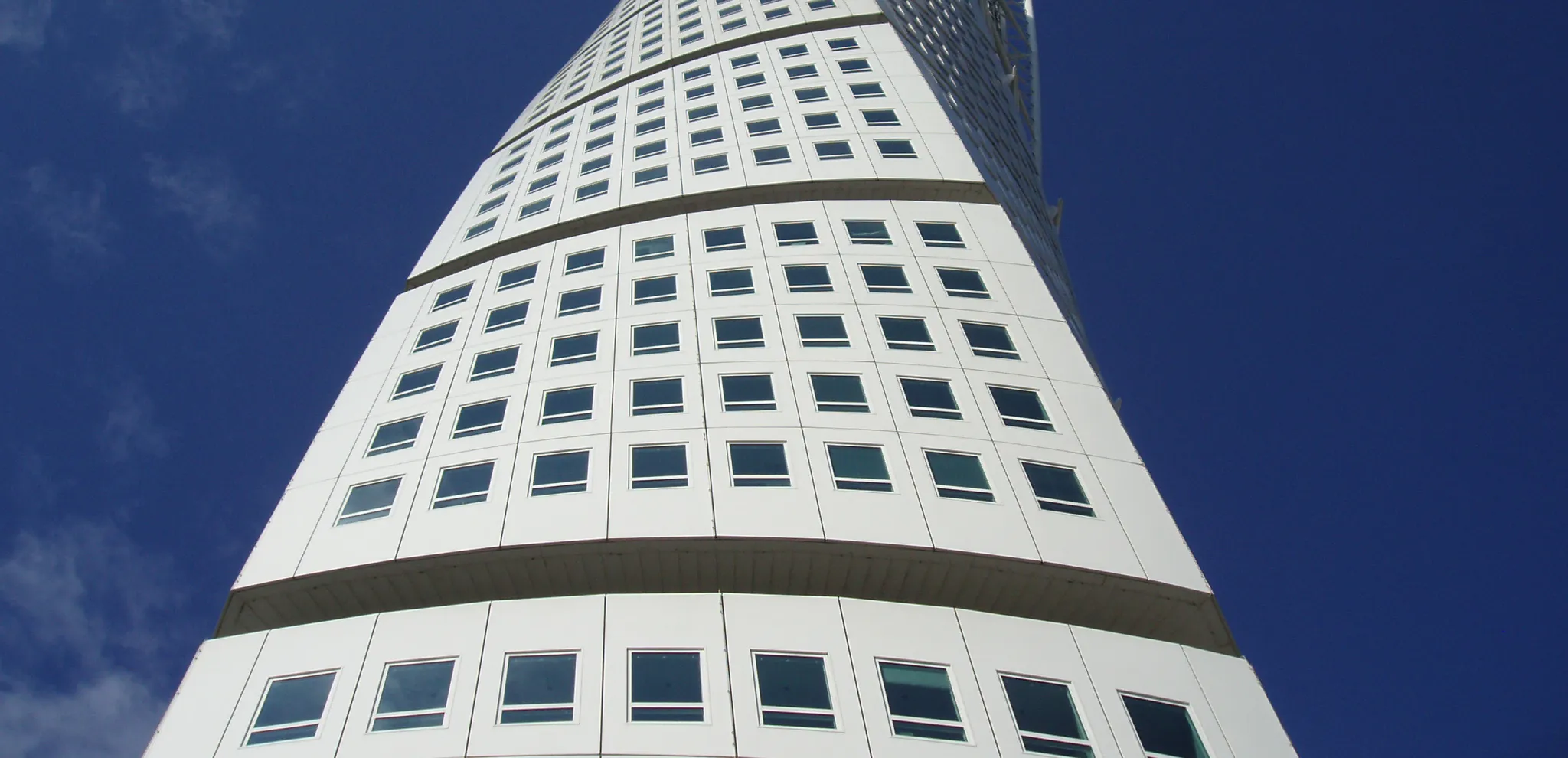 Blick von unten auf den gewundenen Wolkenkratzer Turning Torso, der sich in den Himmel zu schrauben scheint.