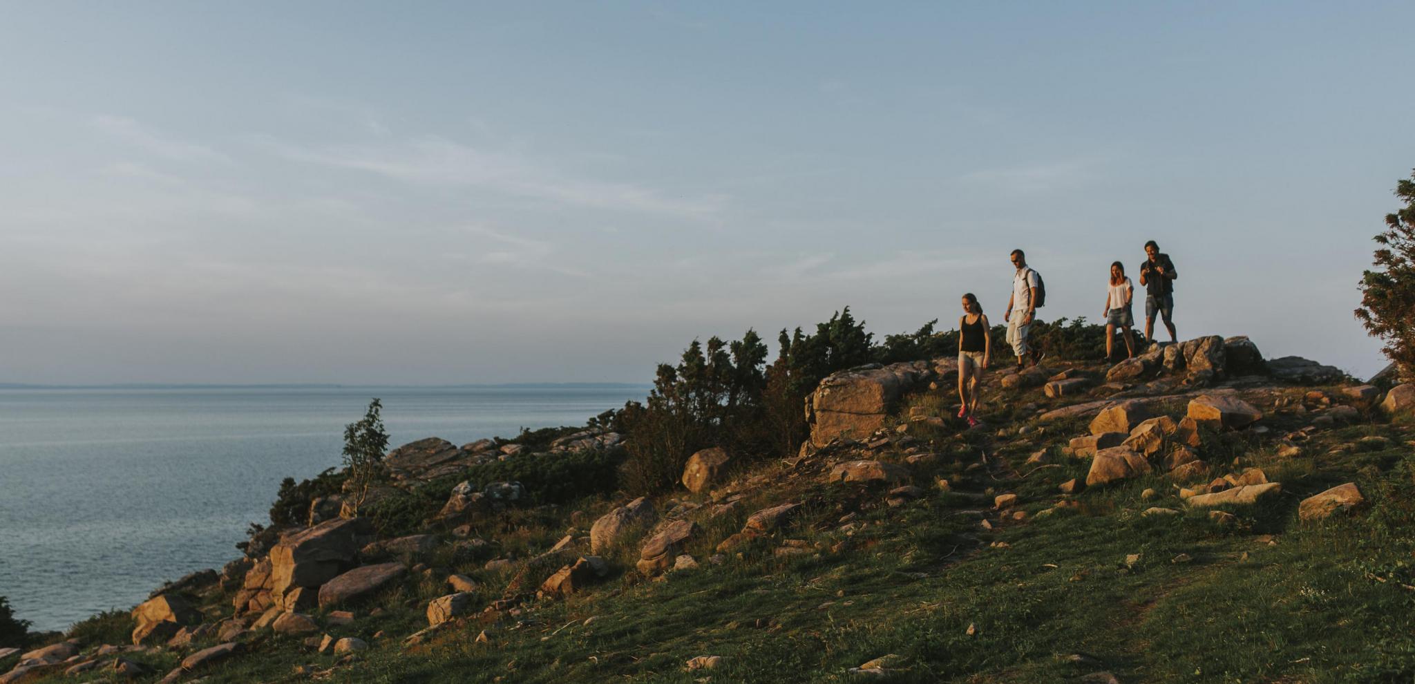 Människor vandrar på klippor vid solnedgången © Mickael Tannus
