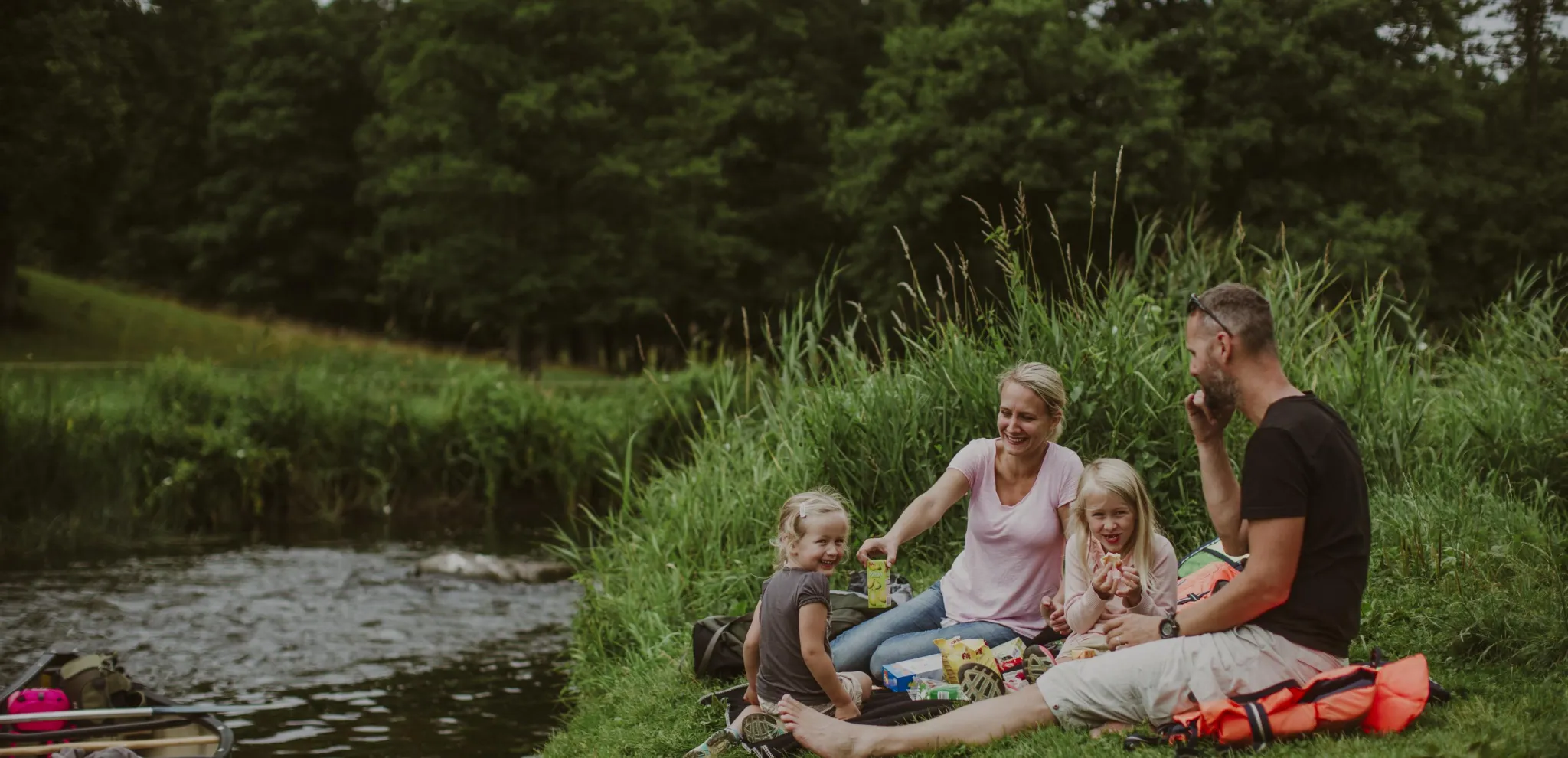 En Familjen sitter och njuter av en picknick vid flodstranden vid Rönne å