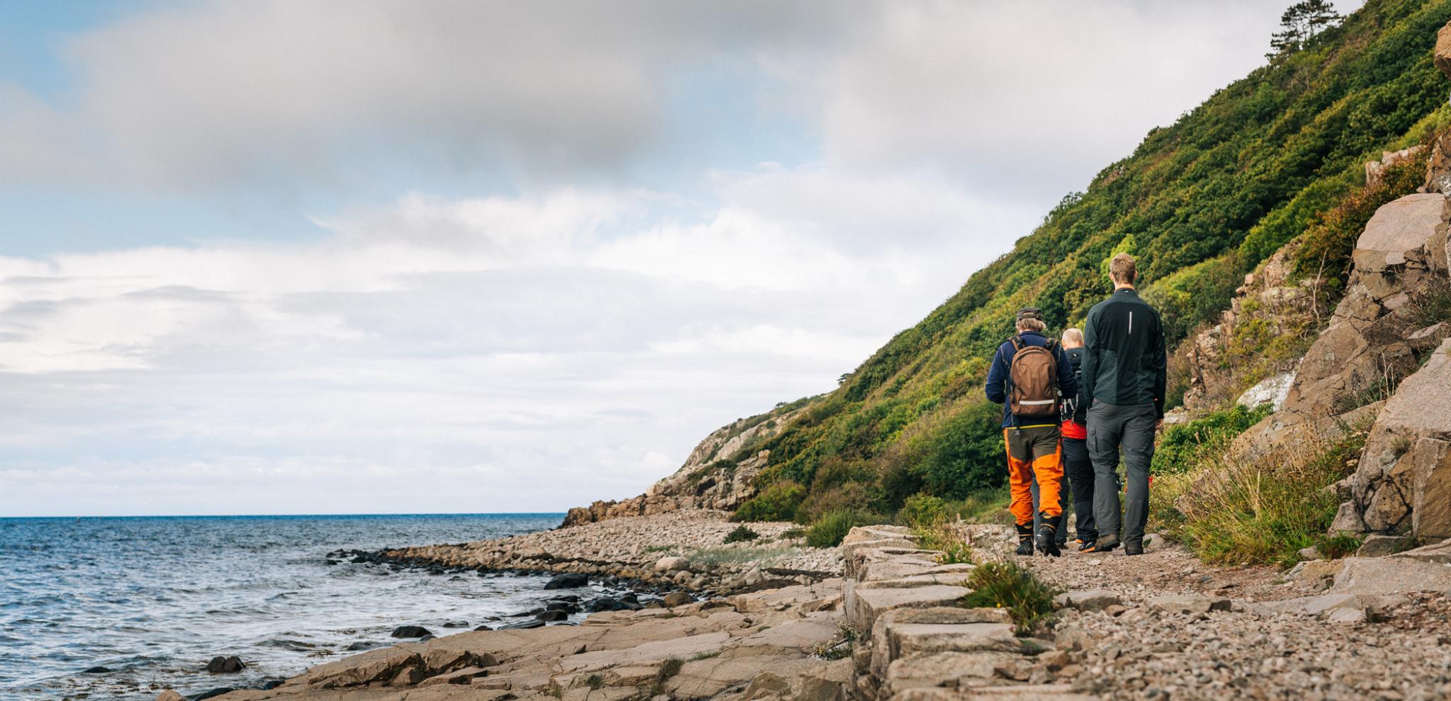 Three people walking next to the sea in Kullaberg