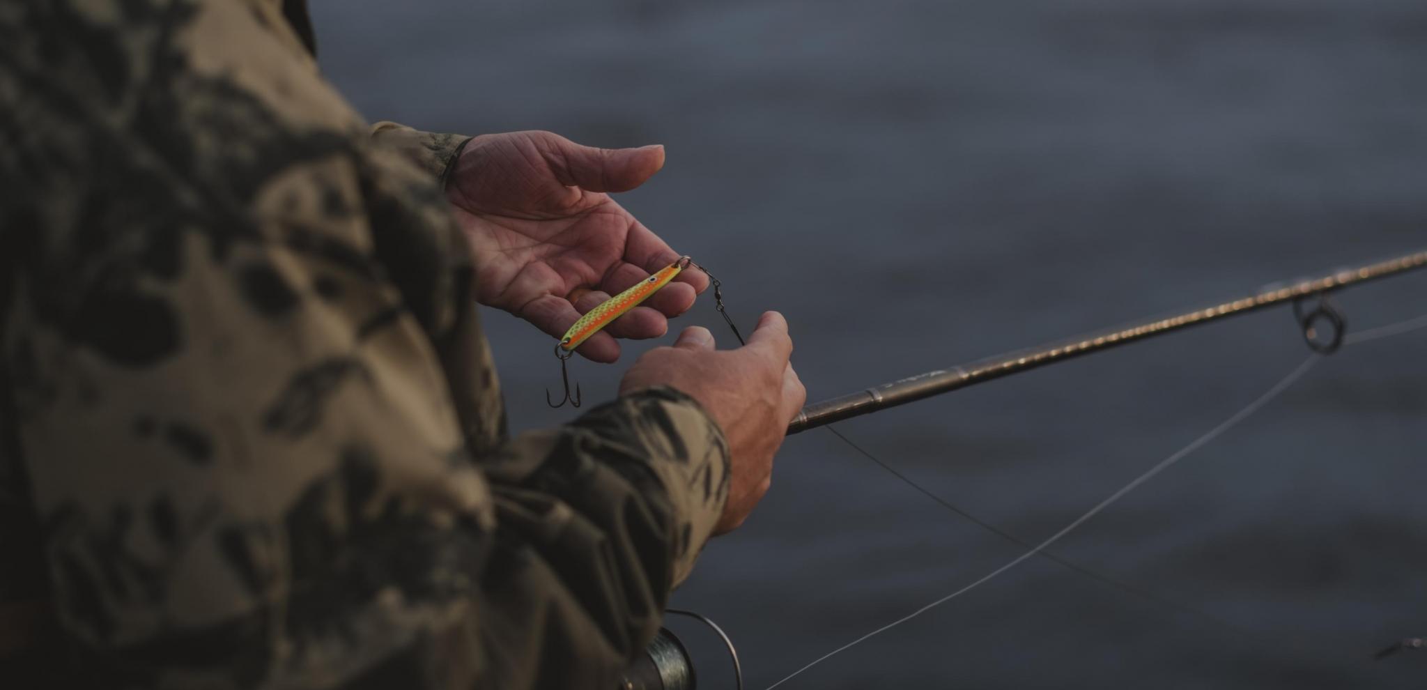 Close up of a man's hands holding a fishingrod and bait