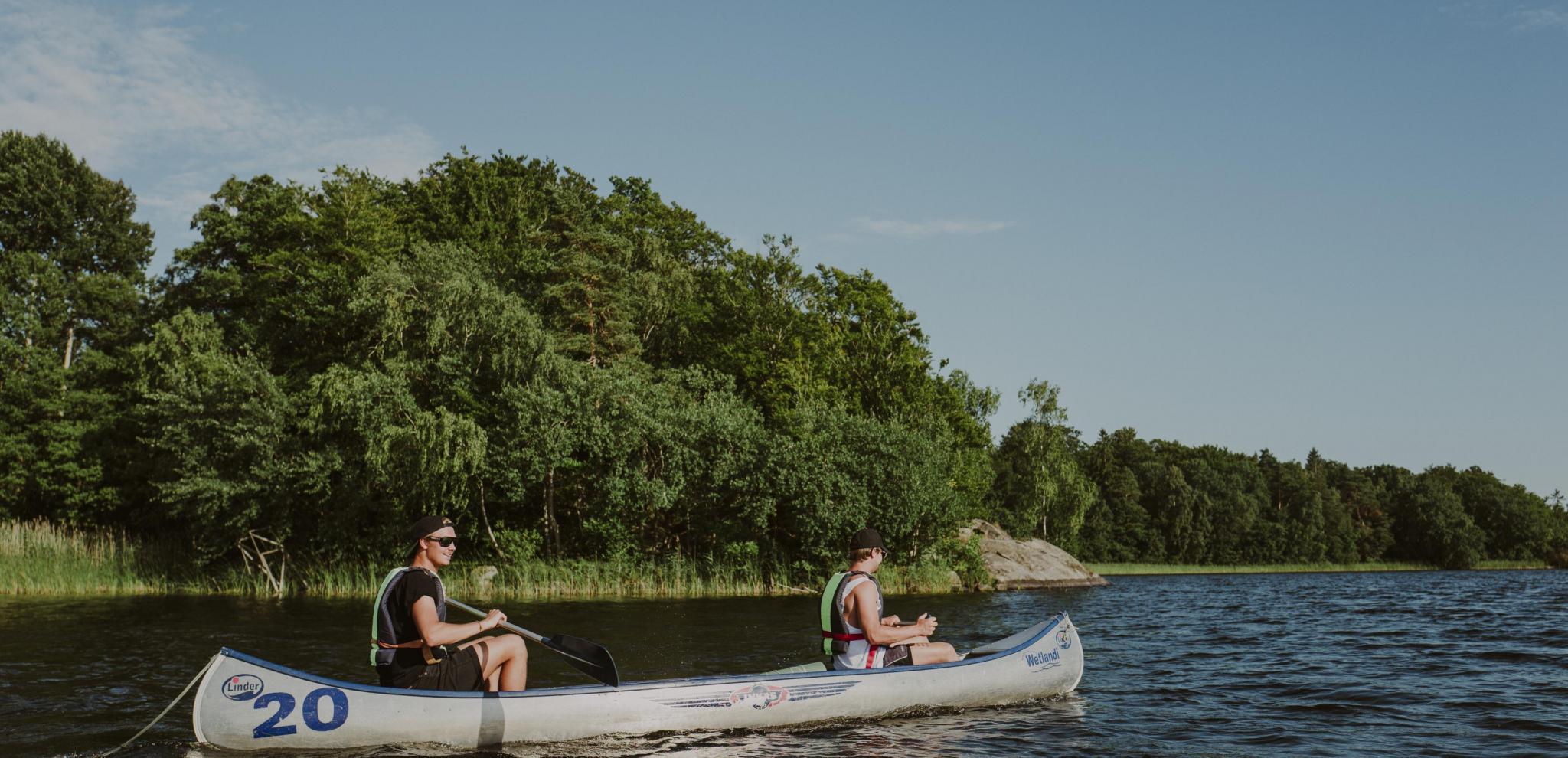 Friends canoeing on a lake with green trees in the background