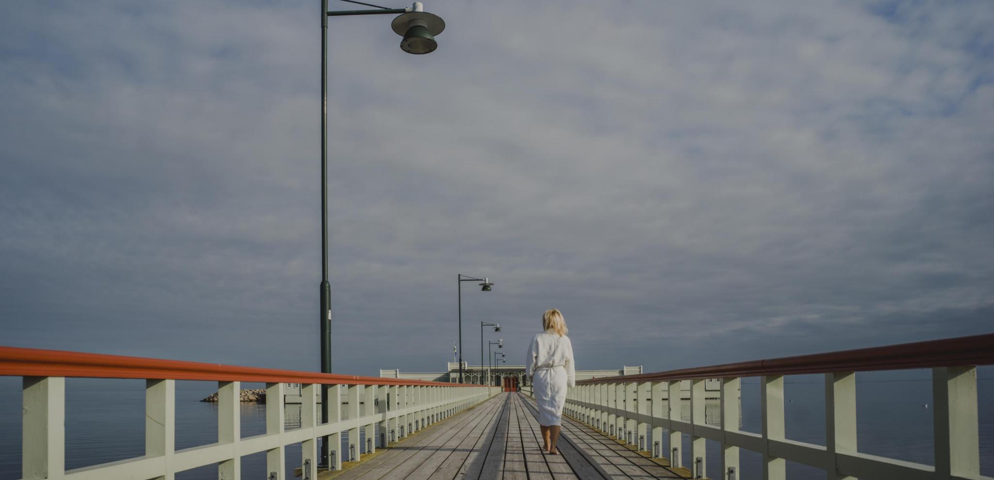 A woman walking towards Ribersborg's cold bath house on a summer day