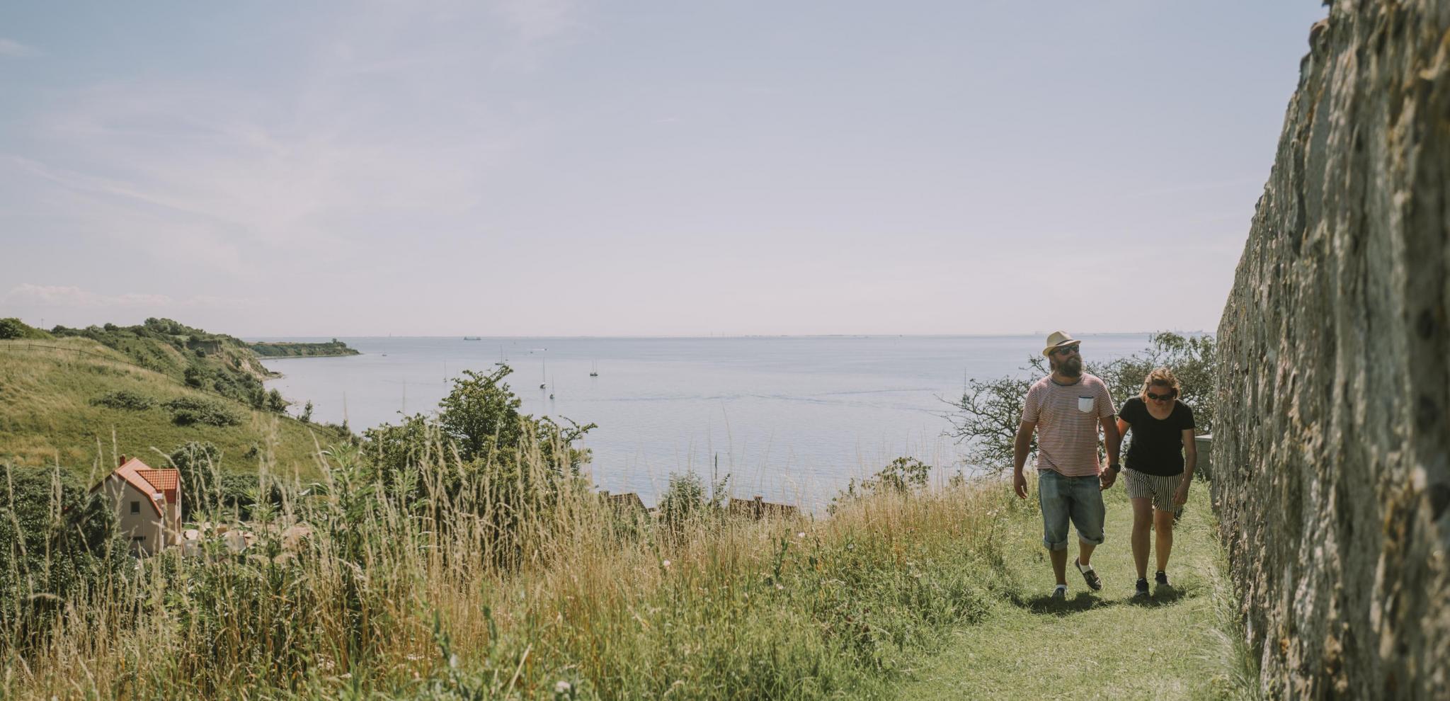 People hiking in countryside during summer with a sea backdrop