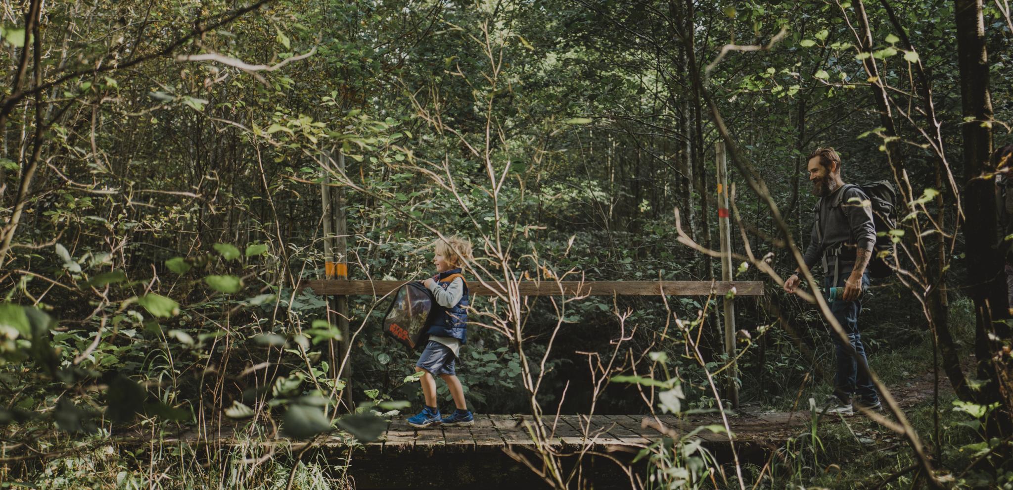 pojke går över en bro över en bäck med sin pappa