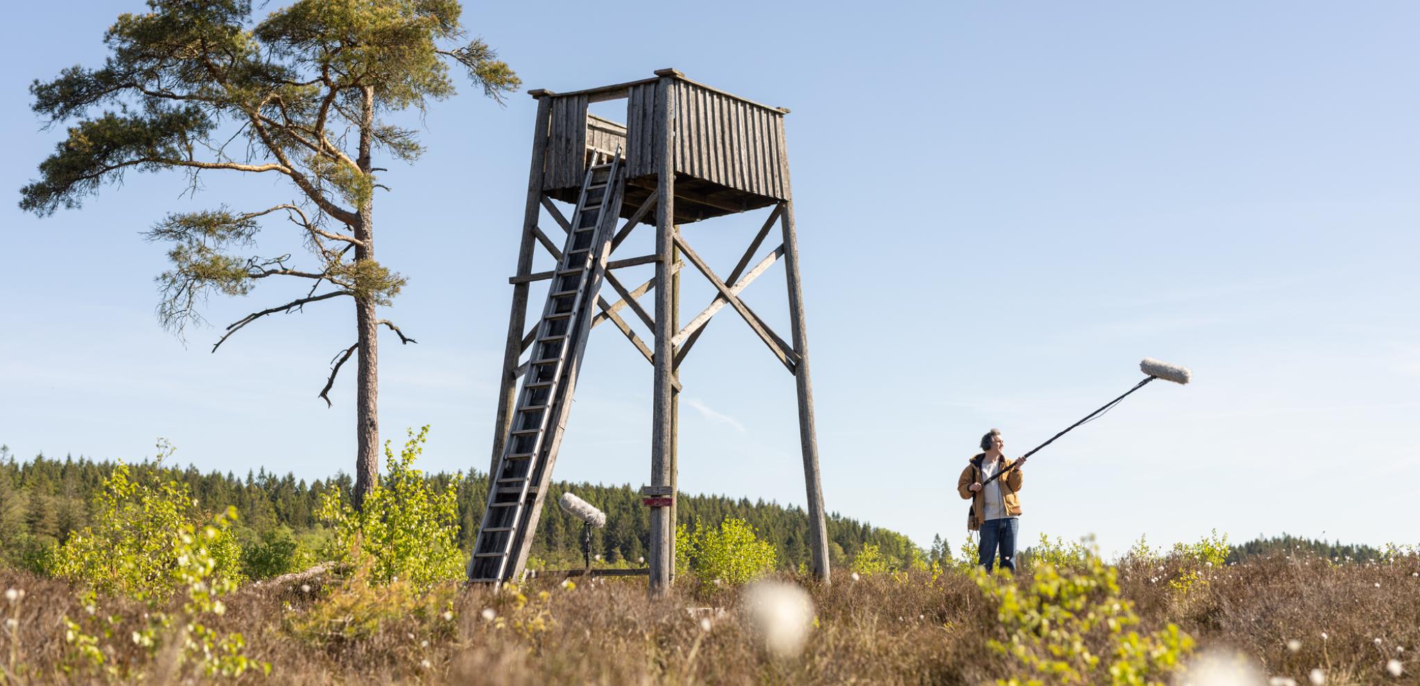 A man standing with sound boom by tower