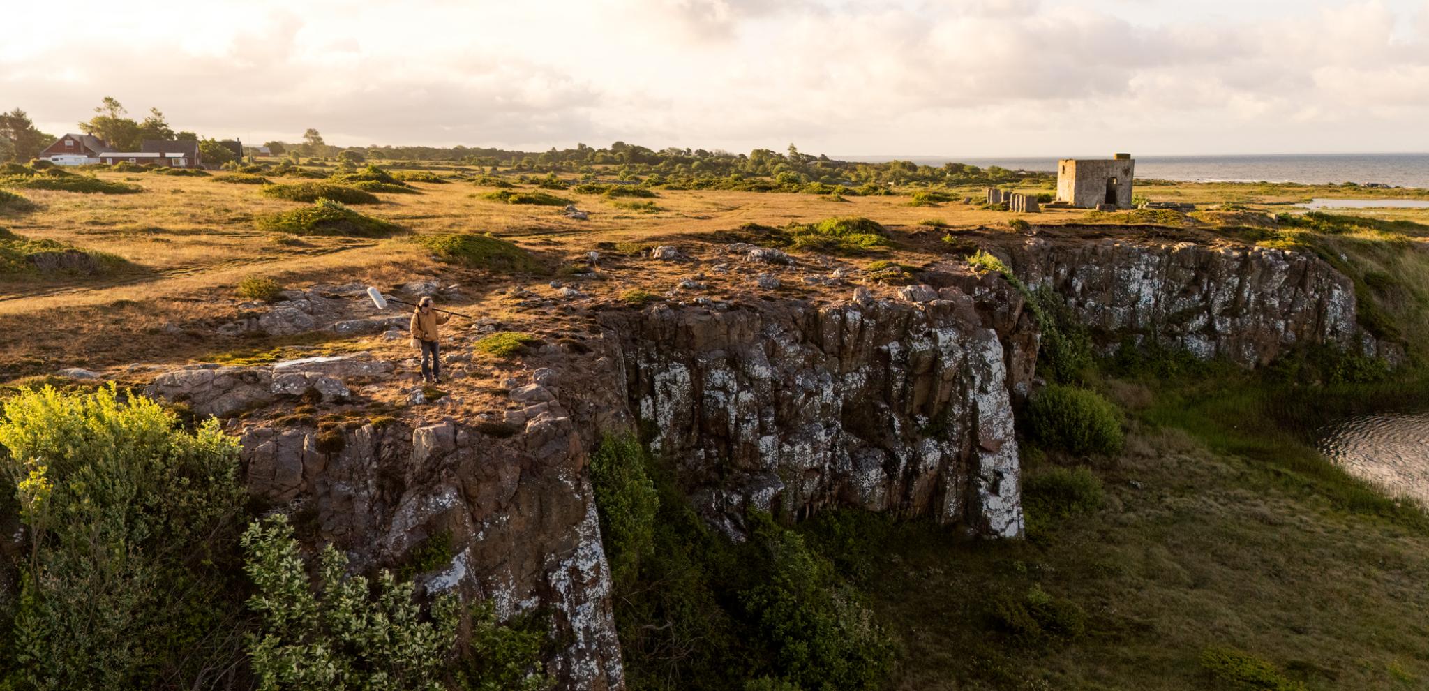 A scenic view of a cliff with a body of water in the distance.