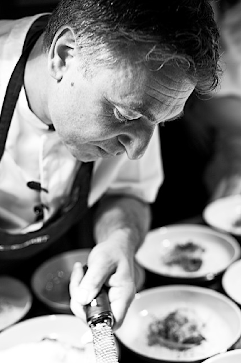 Närbild av kock som framåtlutad lägger upp mat på tallrikar