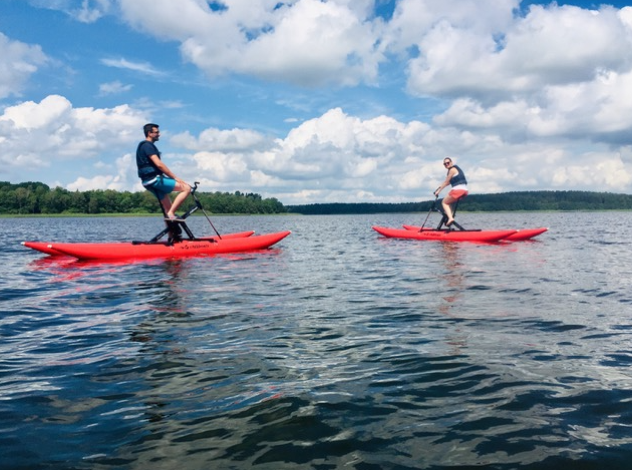Ein Paar fährt im Sommer mit Tretkatamaranen über einen See.