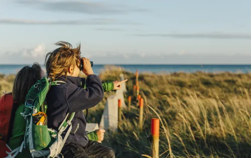 Mutter und Sohn schauen durch ein Fernglas im Naturschutzgebiet Måkläppen.