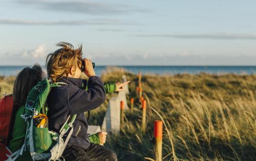 Mutter und Sohn schauen durch ein Fernglas im Naturschutzgebiet Måkläppen.