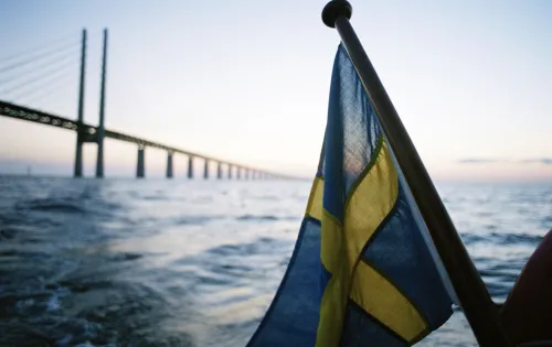 Swedish flag in front of the Öresund Bridge taken from the sea