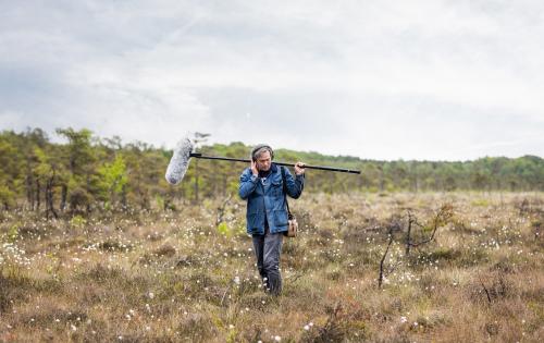 A man in a field holding a microphone.