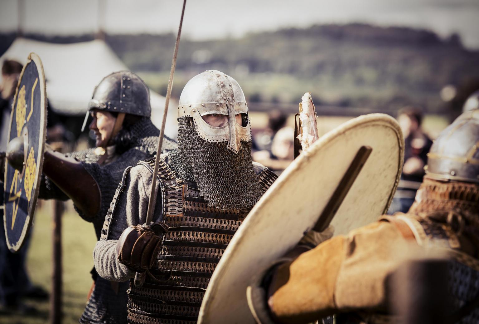 Vikingar med svärd och rustning i en vikingby