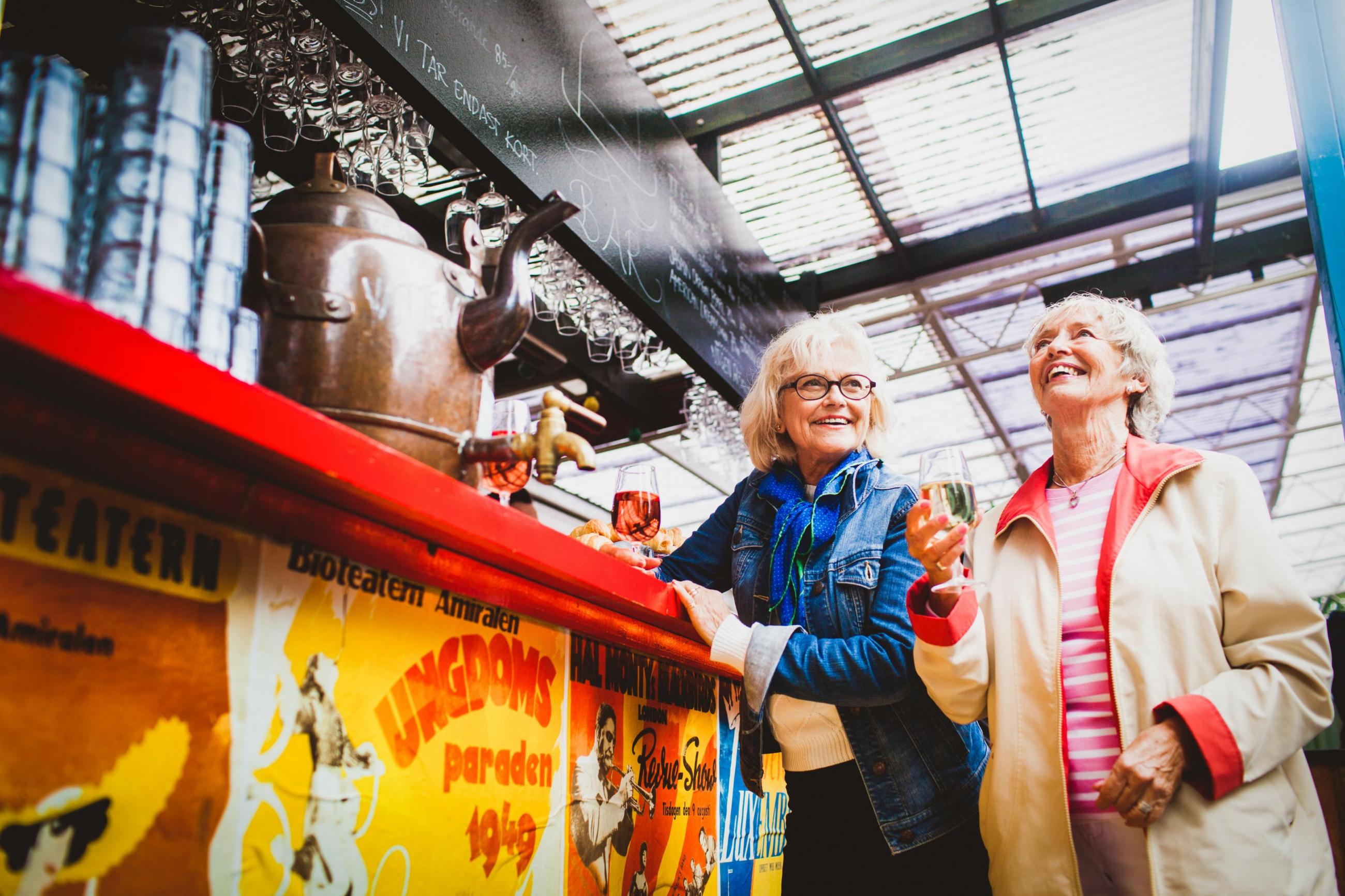 Two women smiling by red and yellow bar