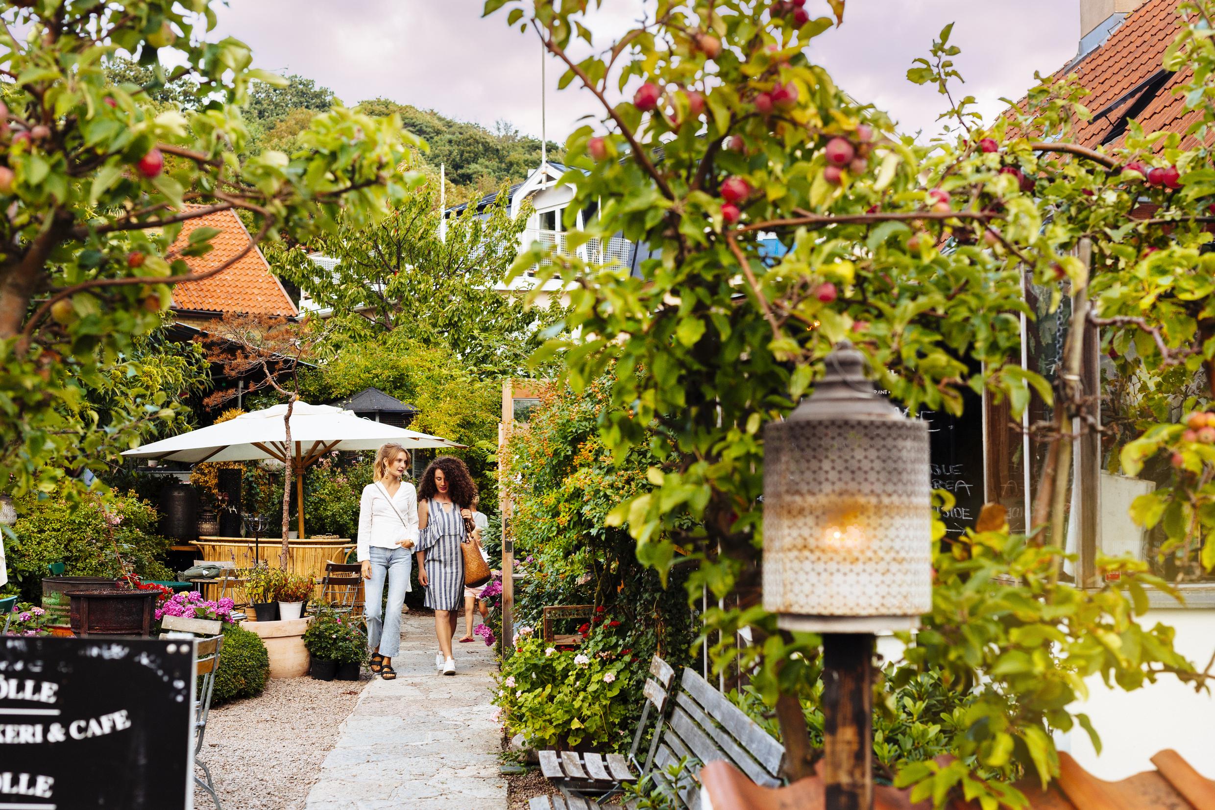 Two women walking in green café garden 