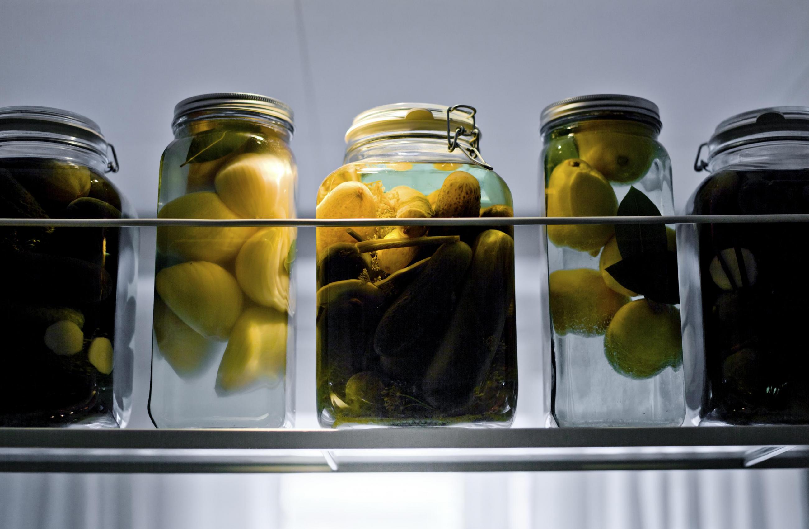 Glasburkar med inlagda grönsaker på en hylla