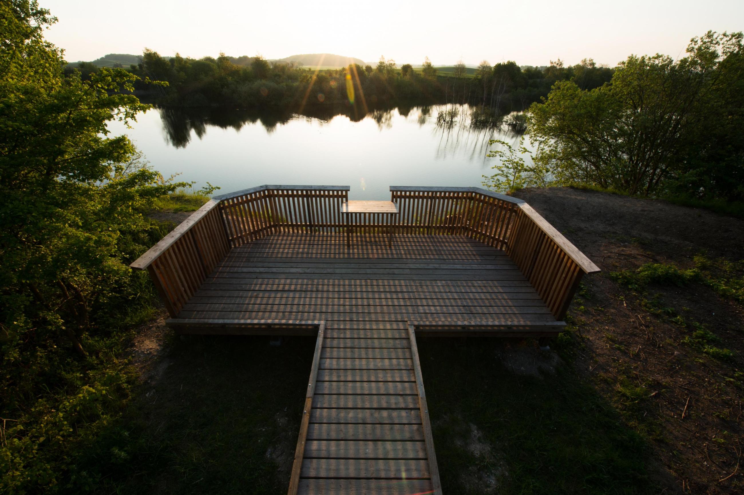 Utsiktsbrygga vid blank sjö i kvällsljus