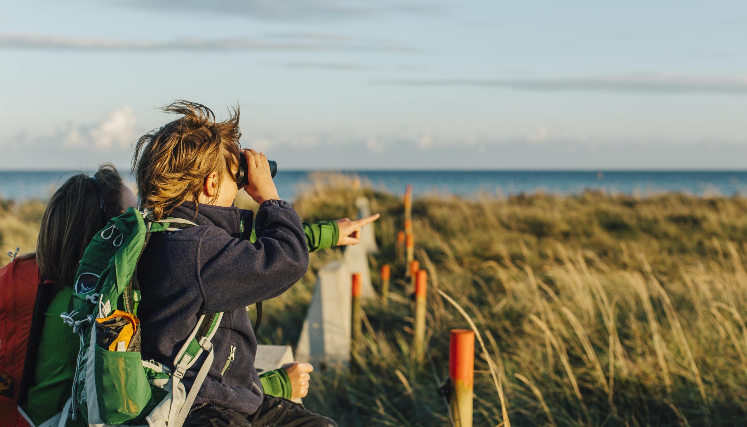 Mutter und Sohn schauen durch ein Fernglas im Naturschutzgebiet Måkläppen.