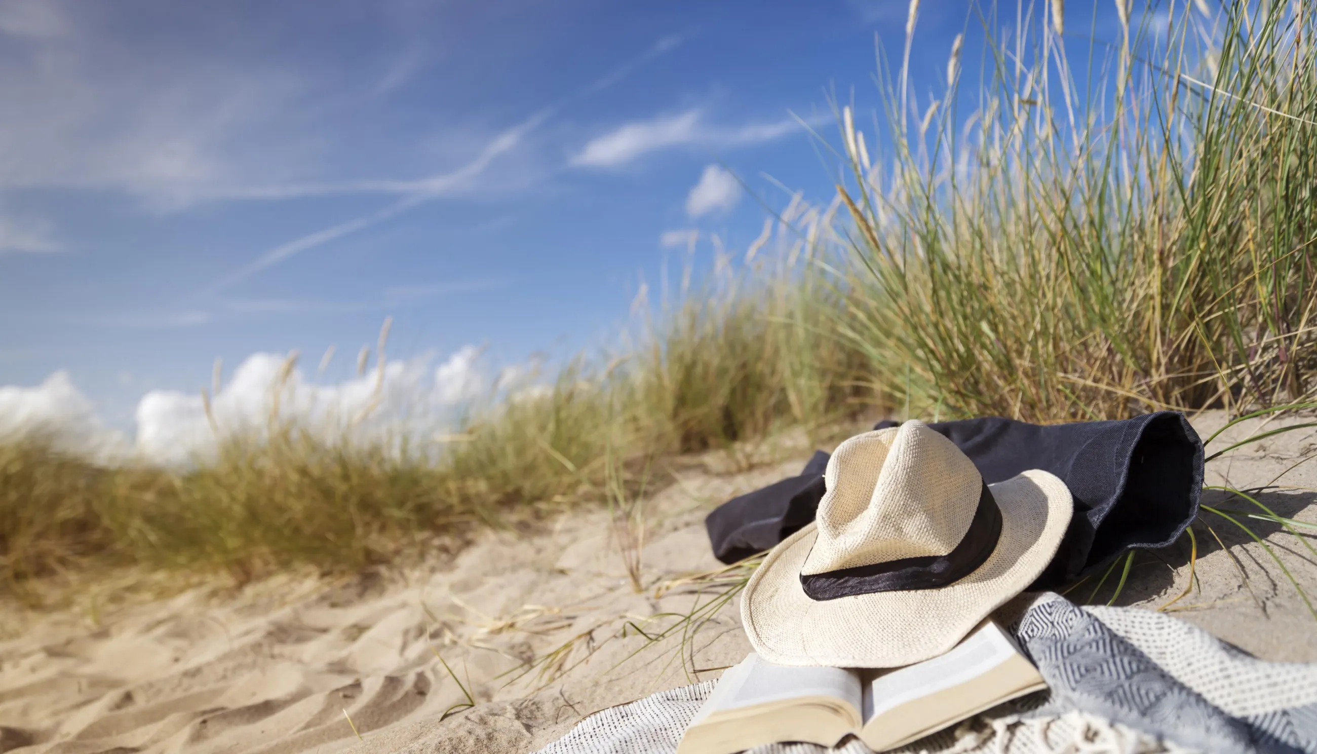 hatt som ligger på en handduk på en sandstrand