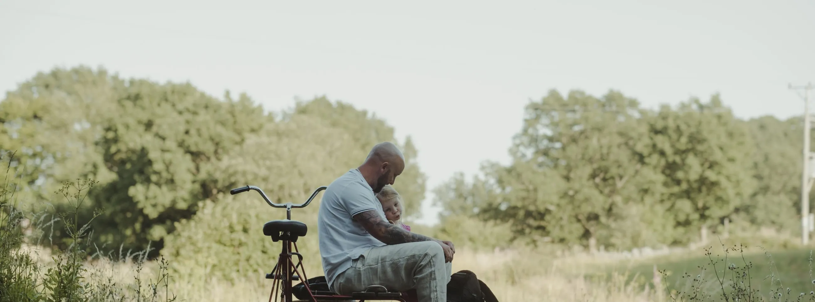 En far sitter tillsammans med sin dotter på en dressin cykel omgiven av naturen