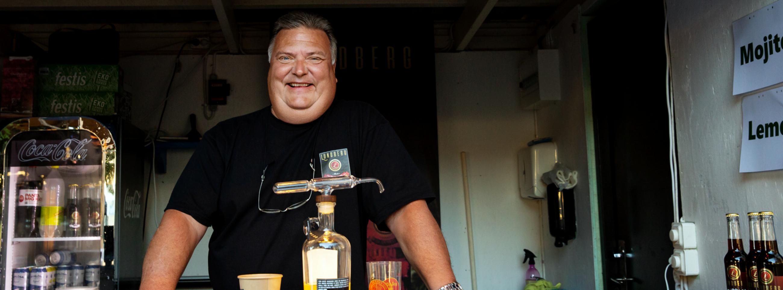 Big smiling man stands behind taps in a bar truck