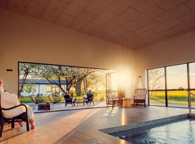 Leute sitzen in Bademänteln und genießen den Sonnenuntergang am Pool des Hotels Mossbylund