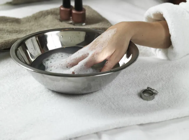 Eine Frau im Bademantel gönnt ihren Händen eine Wellnessbehandlung.