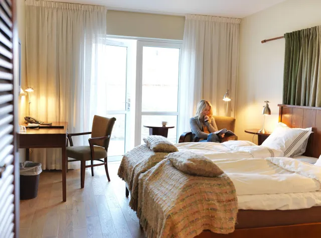 Eine Frau liest ein Buch in einem Hotelzimmer.