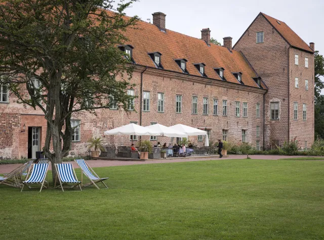 Vor dem Schloss Bäckaskog essen Gäste im Freien.