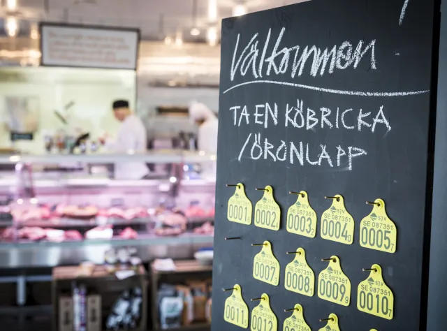 Willkommensschild mit Nummerntafeln vor der Verkaufstheke der Fleischerei Lindegrens in Ängelholm.