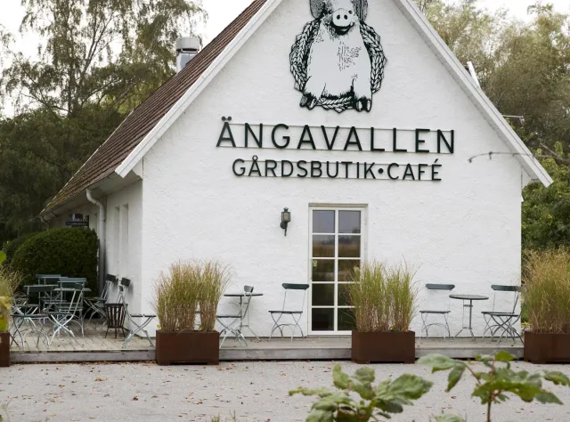 Vorderansicht des Bauernhofs Ängavallen mit Hofladen, Café und Tischen im Freien.