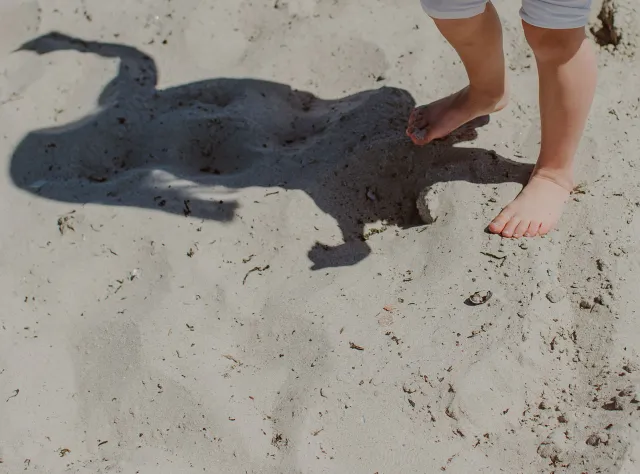 Ett barn står på en sandstrand i Skåne