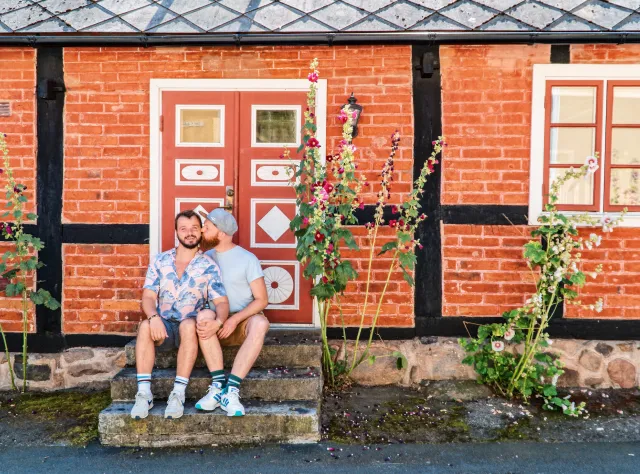 Ett par män som sitter i en trappa som omges av blommor i Kivik