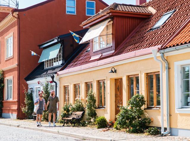 A couple of men holding hands while walking down a street in Ystad