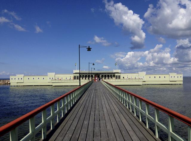 Pier leading to green open-air bathhouse 