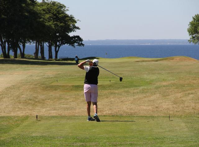 Golfer swinging his bat towards the sea 