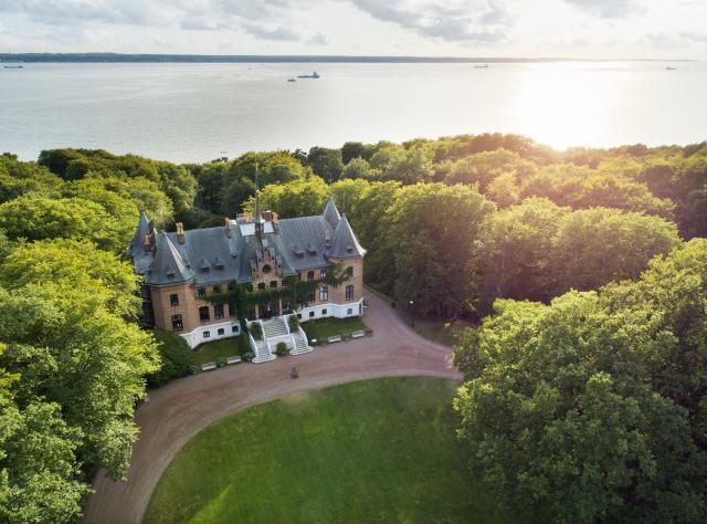 A view from above of Sofiero castle in front of the sea and souronded by trees