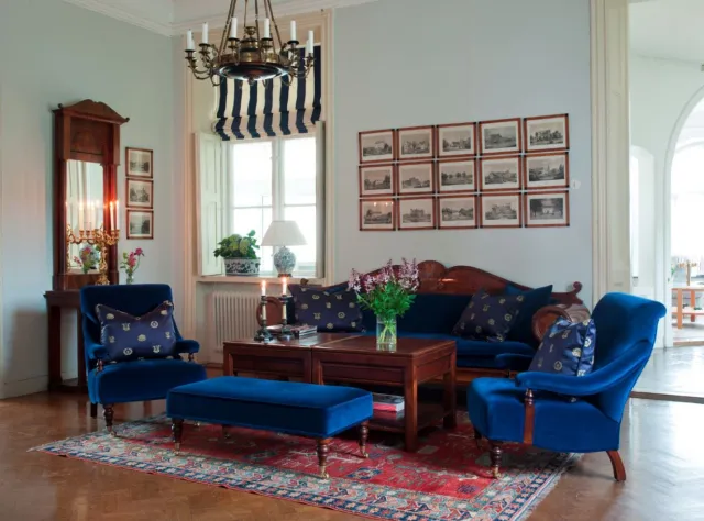 Ein gemütliches Zimmer im Schloss Bjärsjölagård mit blauen Sitzmöbeln und rotem Teppich.