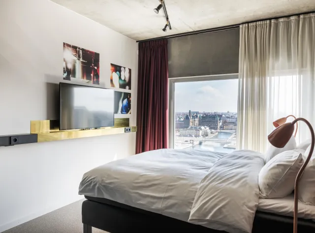 Zimmer im Story Hotel mit Doppelbett, Flachbildfernseher, Stuhl und großem Fenster mit Aussicht.
