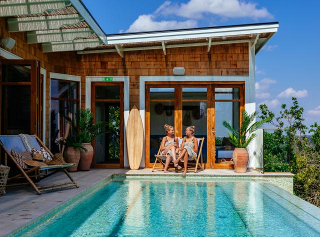 Two women relaxing in sun chairs by a pool