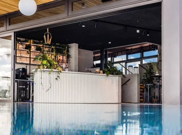 Blick auf eine Rooftop-Bar mit Pool im Vordergrund.