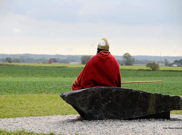 Man sitting on a stone looking out over a field. 